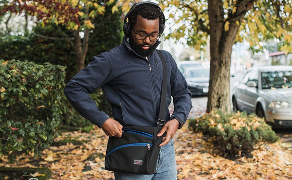 A person accessing the main pocket of the Icon while wearing it cross-body.